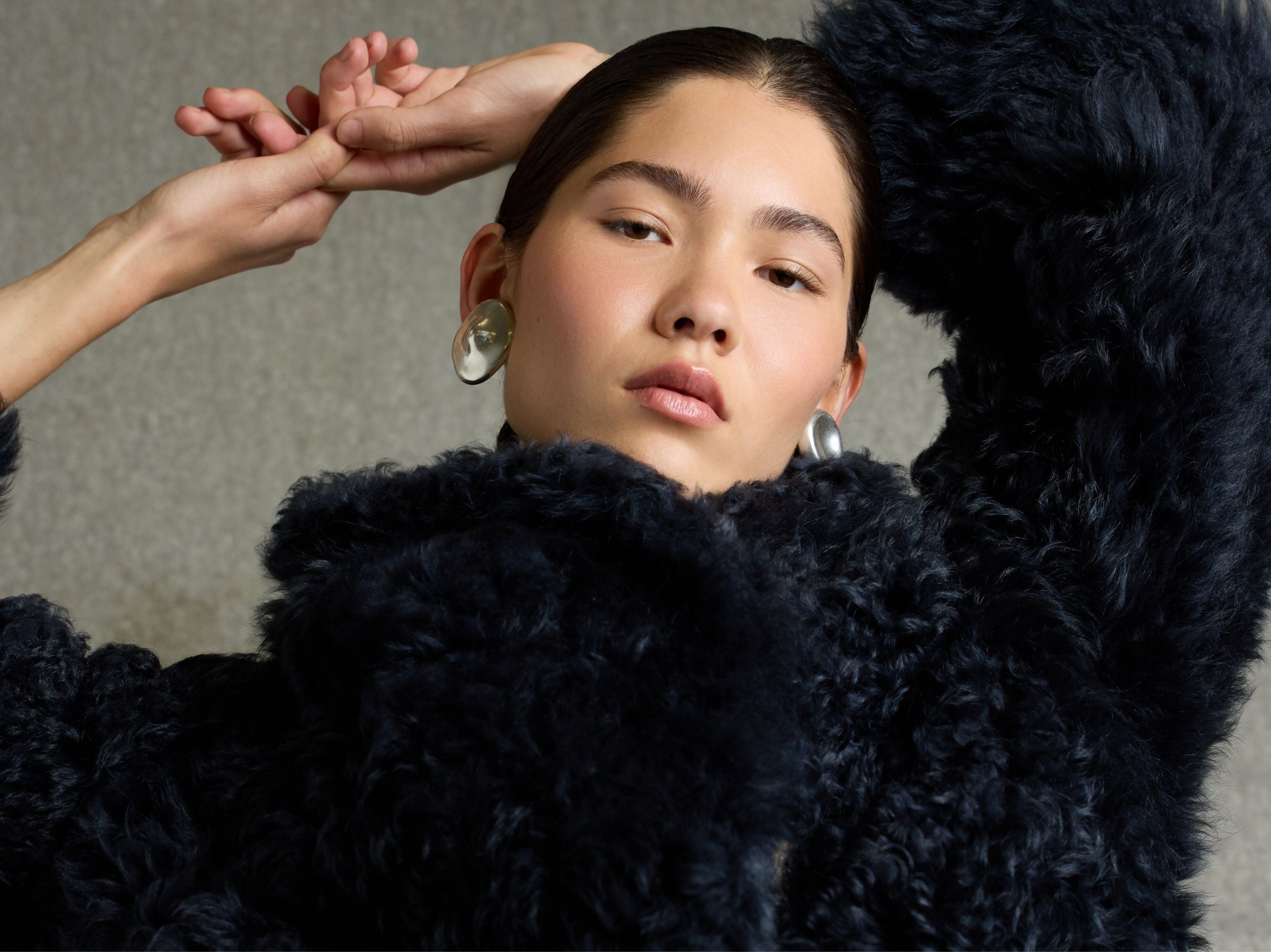 woman wearing navy blue curly shearling jacket - header image luxury womens shearling gushlow & cole