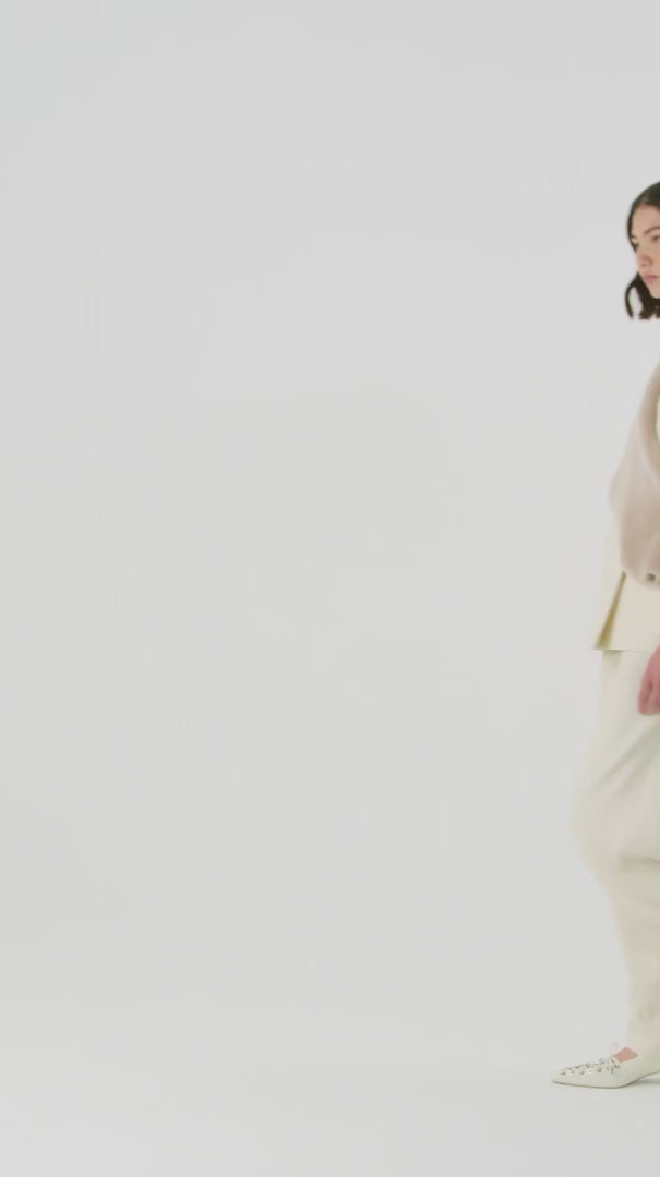 woman wearing cream merino shawl scarf by gushlow & cole over cream matching two piece suit on white background