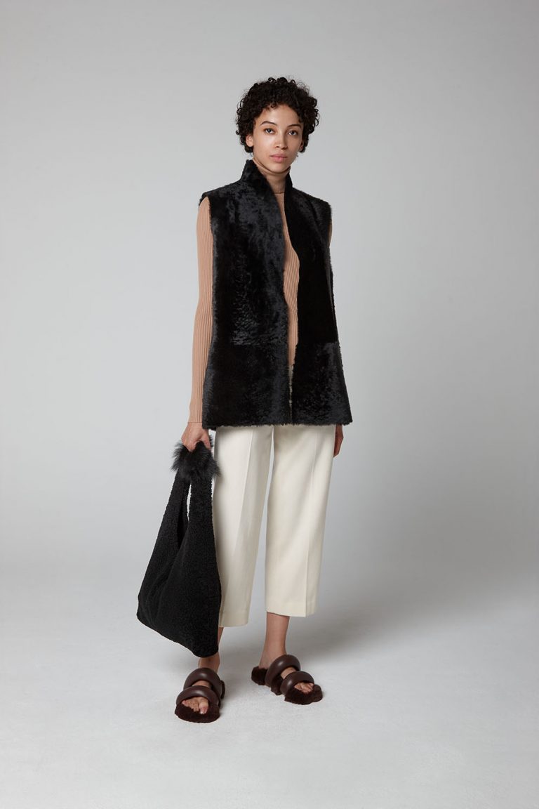Black Short Crombie Shearling Gilet - model full length with bag - women | gushlow & cole
